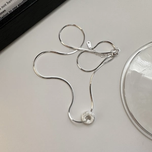Minimalist S925 sterling silver necklace with textured sand donut pendant on beige surface