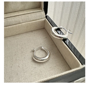Macro detail of polished silver U-shaped hoop earrings in a minimalist jewelry box