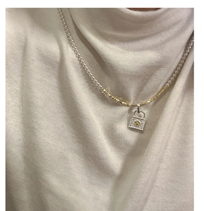 Detail of S925 silver lock pendant with gold flower on pearl and gold link chain