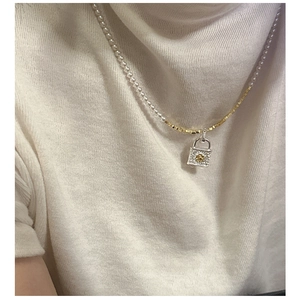 Detail of S925 silver lock pendant with gold floral pattern on pearl and box chain