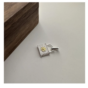 Detail of S925 silver lock pendant with golden flower and hammered metal texture