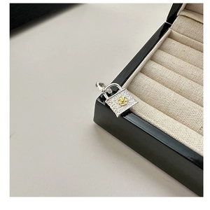 Macro shot of silver square lock pendant with gold floral motif and vintage texture