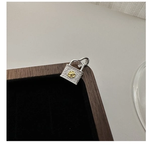 Macro detail of S925 silver vintage lock pendant with floral engraving and golden flower
