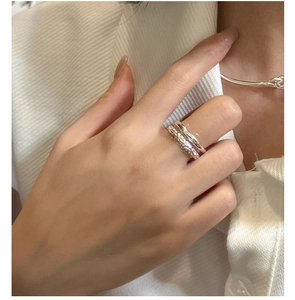 Detail of layered S925 sterling silver rings with hammered texture on female hand