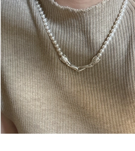 Close-up of S925 silver hands clasp on a delicate pearl choker necklace worn on knitwear