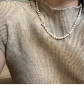 Close-up of elegant small white pearl necklace with silver clasp on woman model