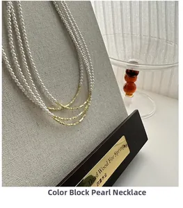 Dettaglio della collana a strati con perle bianche e perle metalliche dorate testurizzate