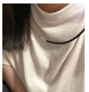 Detail of S925 silver necklace featuring black onyx beads and asymmetric chain on a model