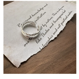Macro detail of S925 sterling silver layered ring with hammered texture on vintage paper