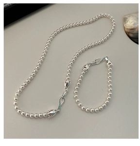 Detailed shot of silver bead necklace and bracelet set with S-shaped floral clasp
