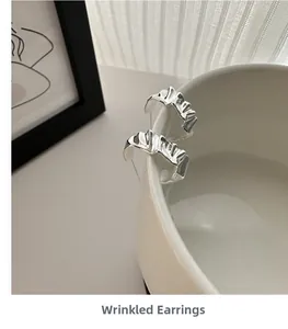 Close-up of S925 sterling silver wrinkled C-shape earring showing irregular texture