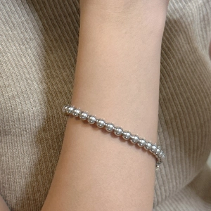 Gros plan d'un bracelet minimaliste en perles d'argent porté au poignet avec style