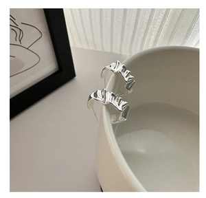 Detailed macro of polished S925 sterling silver hallmarking on irregular crinkled C-earrings
