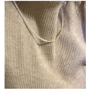 Dettaglio della collana in argento S925 con perle e barre dorate su maglione beige