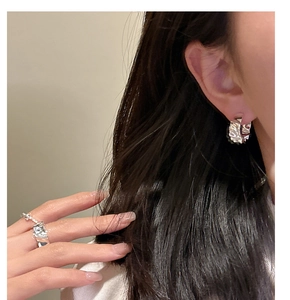 Close-up of S925 sterling silver earrings and ring with irregular hammered texture on model