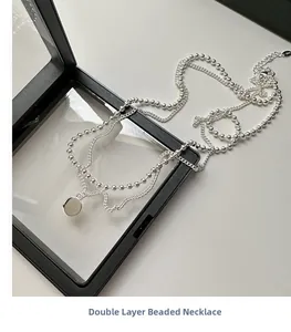 Détail de collier double rang argenté avec chaîne à billes et pendentif miroir rond