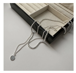 Vue détaillée du collier double rang en argent S925 avec pendentif rond poli minimaliste