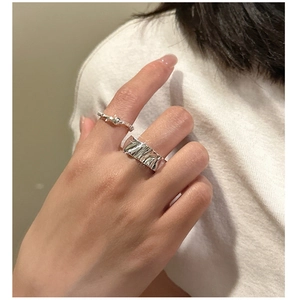 Detail of silver S925 crumpled texture ring and minimalist beaded band worn on hand