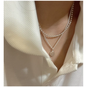 Gros plan du collier double rang en argent S925 avec pendentif rond poli brillant
