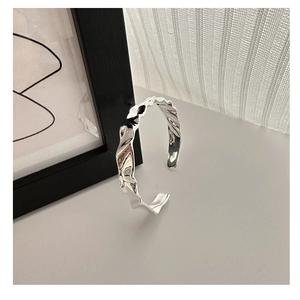 Macro del marchio S925 sul bracciale rigido aperto minimalista con design plissettato irregolare