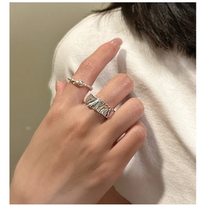 Detail of S925 sterling silver wrinkled ring and minimalist thin band on finger