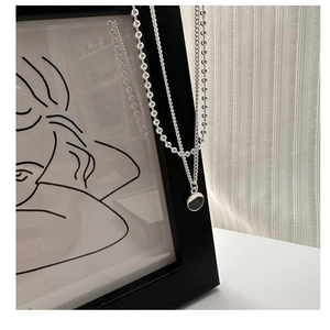Vue détaillée d'un collier à double épaisseur en argent S925 avec pendentif rond poli