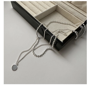 Gros plan détaillé du collier double couche en argent S925 avec pendentif rond dans sa boîte