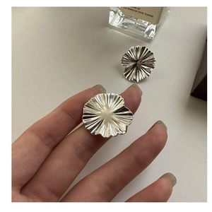 Macro shot of silver textured floral earrings with detailed radiating fold patterns