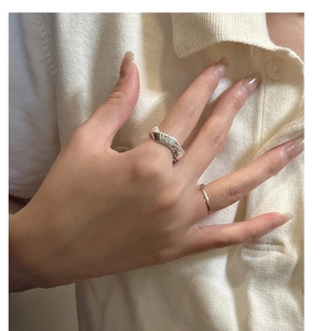 Detail of stacked 925 silver wave letter ring and slim gold ring on model finger