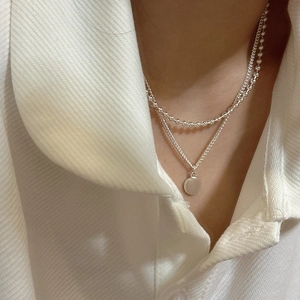 Collier double rang en argent S925 avec pendentif rond épuré sur une chemise blanche