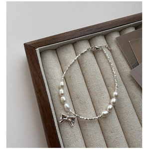 Detail of S925 silver bow pendant and freshwater pearls on a delicate beaded bracelet