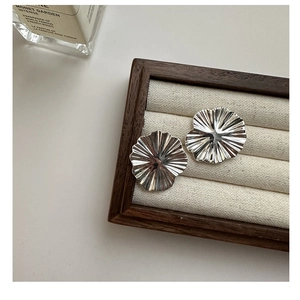 Macro shot of silver S925 floral earrings featuring irregular wrinkled metallic petals