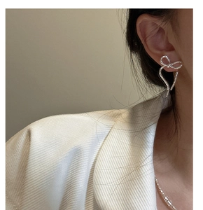 Close-up of S925 silver bow earrings with textured surface worn by a model