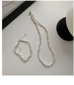 Detailed view of the layered S925 silver necklace and bracelet with woven pearls