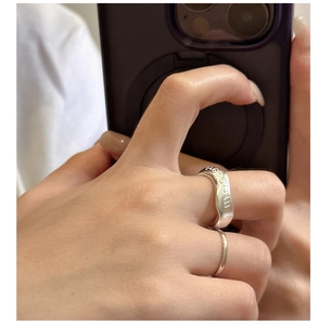 Detail of silver MOM engraved wave ring and slim band on person holding a phone