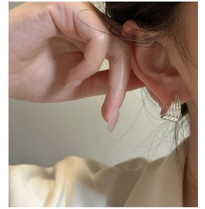 Macro shot of silver layered hoop earrings with wavy texture on a female model
