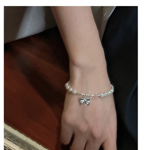 Detail of s925 silver bow pendant and white pearls on a sweet style handmade bracelet