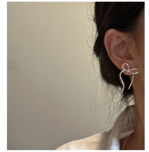 Detail view of S925 sterling silver bow earrings with textured brushed metal finish