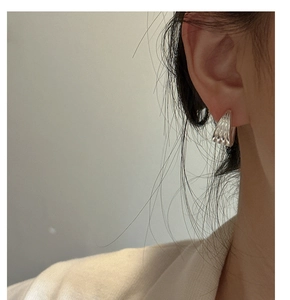 Macro detail of S925 sterling silver multilayer textured hoop earrings on a model