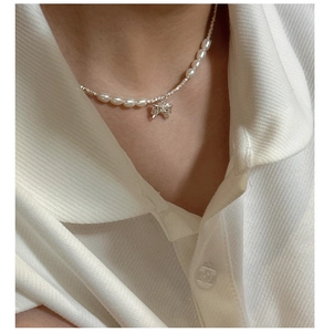 Detail of s925 silver bow necklace with elegant white pearls on a model's neck