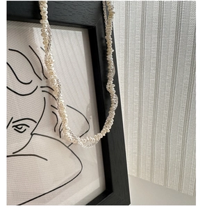 Detail of twisted S925 silver chain entwined with natural white baroque pearls