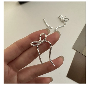 Detail view of hammered silver bow earring with textured finish and ribbon design