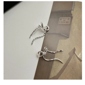 Detail of S925 sterling silver bow earrings with a hammered texture and ribbon design