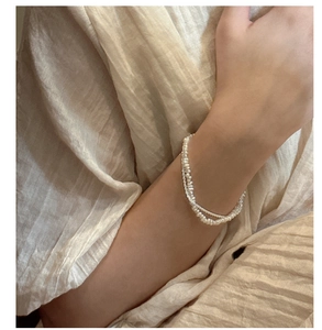 Detail of layered S925 silver bracelet featuring natural white pearls on a model wrist