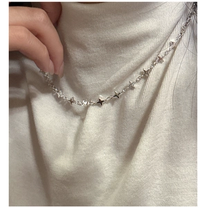Detail of silver S925 star necklace featuring multiple four-pointed star pendants on a model