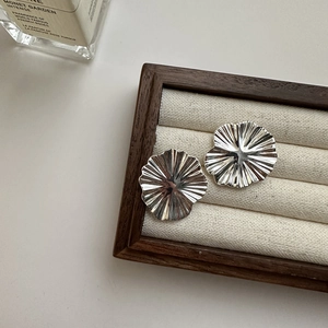 Polished S925 sterling silver floral stud earrings with wavy pleated design on a tray