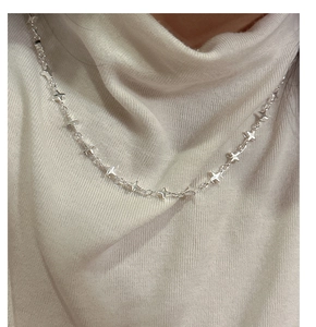 Detail of S925 silver necklace with small star charms worn over a white sweater