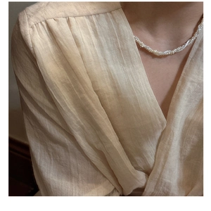 Detail showing layers of small white pearls in a twisted strand French style necklace