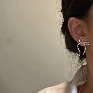 Elegant S925 sterling silver ribbon bow earrings on model with handcrafted texture