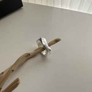 Minimalist S925 sterling silver ring with freedom engraving on a natural wood stand